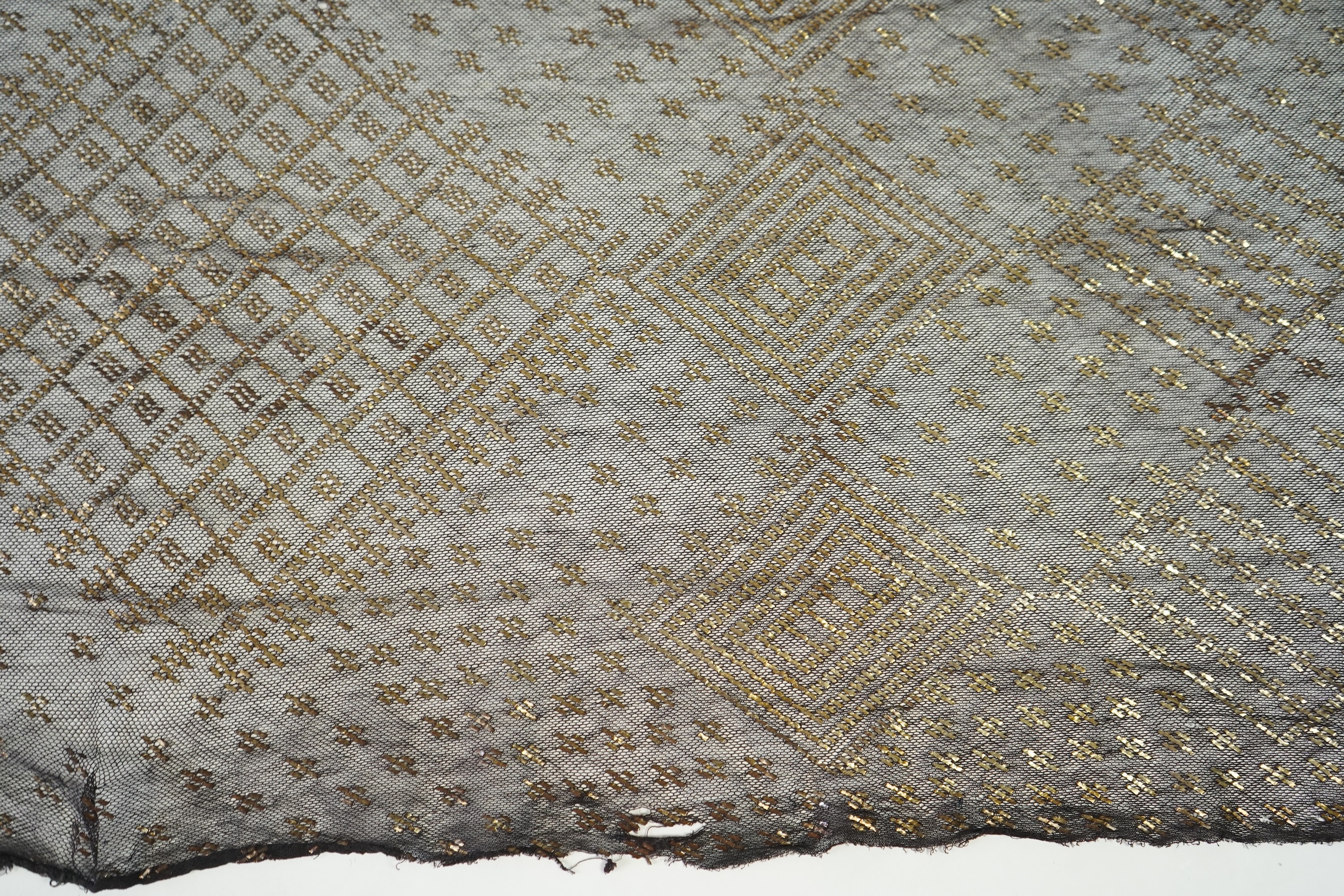 A 1930’s Egyptian decorative metal on black net evening stole. Approximately 218cm long. Condition - the rolled edges are frayed but the colour and design are intact.